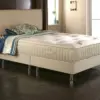 Cashmere-1 - Jamies Furniture Beige upholstered bed with a thick mattress and layered blue-green bedding in a modern dark-floored bedroom.