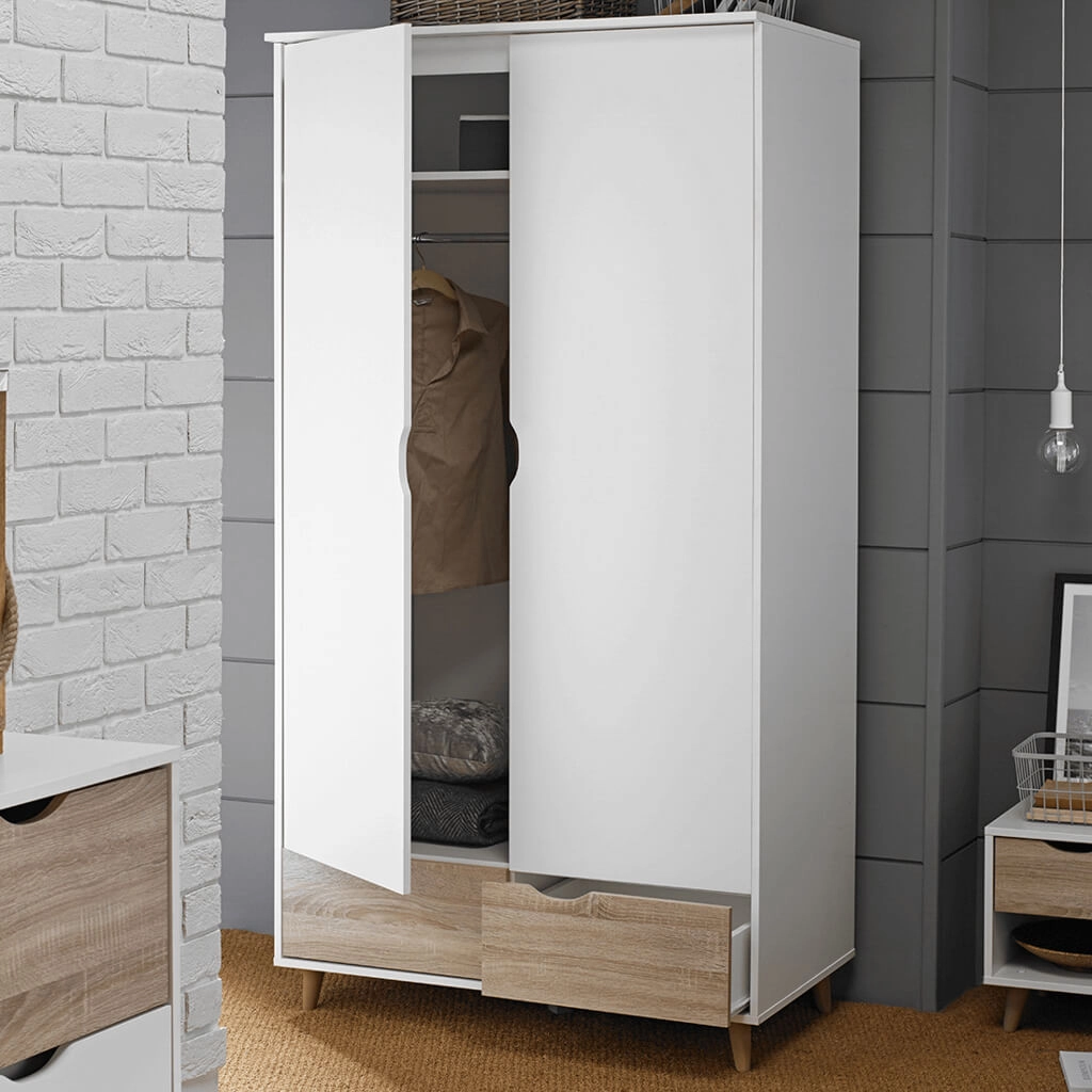 White freestanding wardrobe with two bottom drawers, one open to reveal a brown coat and folded textiles inside.
